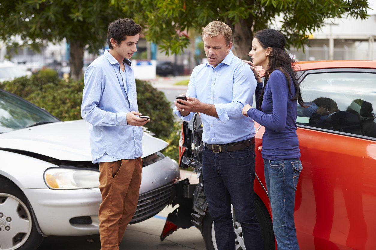 Three drivers exchanging insurance information after a car accident.
